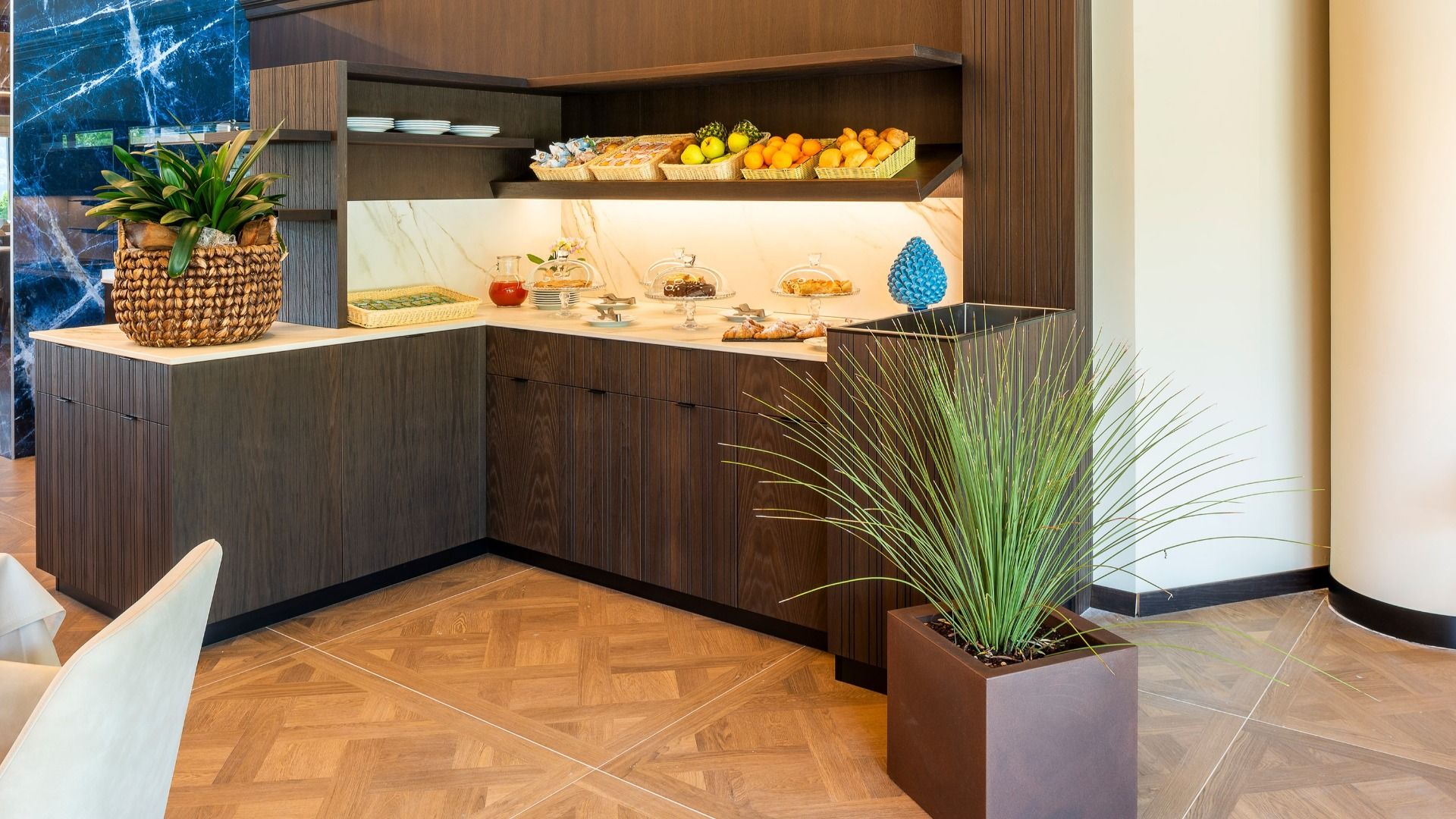Ein modernes Buffet mit Holzschränken, frischem Obst und Snacks erwartet Sie im stilvollen Speisesaal des Sporthotels Olimpo - ideal für Gäste, die sich nach einer Runde Tennis am Gardasee erholen möchten.