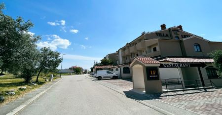 Luftaufnahme der mediterranen Stadt mit dem Hotel Villa Letan, das f&uuml;r seinen Wert bekannt ist und rote Ziegeld&auml;cher, einen Pool, einen Sportplatz und &uuml;ppiges Gr&uuml;n unter einem klaren blauen Himmel aufweist.