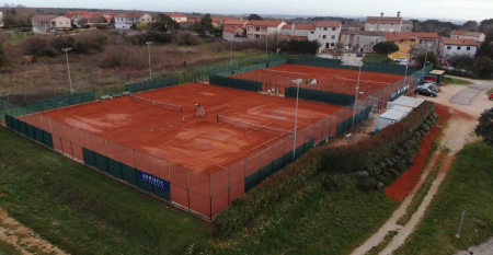 Luftaufnahme der mediterranen Stadt mit dem Hotel Villa Letan, das f&uuml;r seinen Wert bekannt ist und rote Ziegeld&auml;cher, einen Pool, einen Sportplatz und &uuml;ppiges Gr&uuml;n unter einem klaren blauen Himmel aufweist.