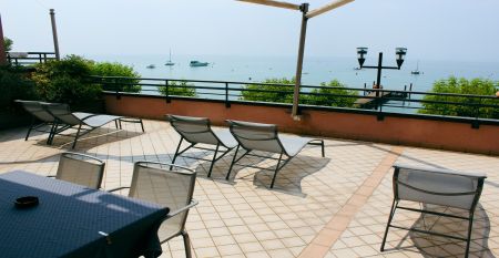 Gartenrestaurant des Hotel Sportsman mit Rattanm&ouml;beln, Sonnenschirmen und gedeckten Tischen auf gepflegtem Rasen.