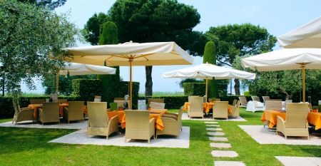 Gartenrestaurant des Hotel Sportsman mit Rattanm&ouml;beln, Sonnenschirmen und gedeckten Tischen auf gepflegtem Rasen.