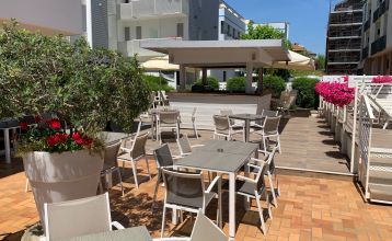 Außenansicht des Hotel RIZ mit Pool, Liegestühlen und spielenden Kindern.