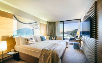 Luftaufnahme des Valamar Padova Hotels 4* – eines Resorts an der Küste mit Pool, Sonnenliegen, Strohsonnenschirmen, Palmen und direktem Zugang zu einem Sandstrand in der Nähe einer historischen Küstenstadt bei Sonnenuntergang. Die Gäste können vielfältige