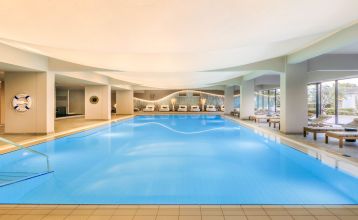 Luftaufnahme des Valamar Padova Hotels 4* – eines Resorts an der Küste mit Pool, Sonnenliegen, Strohsonnenschirmen, Palmen und direktem Zugang zu einem Sandstrand in der Nähe einer historischen Küstenstadt bei Sonnenuntergang. Die Gäste können vielfältige