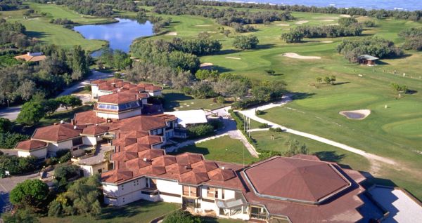 Luftaufnahme der üppigen Fairways, Sandbunker, Wasserhindernisse und des markanten Clubhauses mit sechseckigem Dach des Albarella Golf Hotels – ideal zur Erholung und für eine ruhige Atmosphäre nach dem Sport.