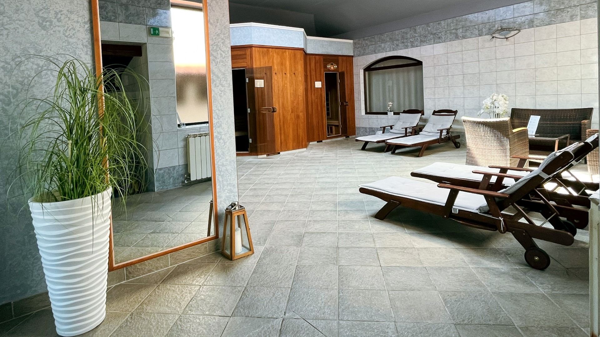 Der Wellnessbereich im Hotel Villa Letan bietet einen Wellness-Ruheraum mit Liegestühlen, einem großen Spiegel, Korbmöbeln, einer Holzsauna und sanftem Tageslicht - eine ruhige Atmosphäre mit einem hervorragenden Preis-Leistungs-Verhältnis.