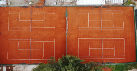 Luftaufnahme der mediterranen Stadt mit dem Hotel Villa Letan, das f&uuml;r seinen Wert bekannt ist und rote Ziegeld&auml;cher, einen Pool, einen Sportplatz und &uuml;ppiges Gr&uuml;n unter einem klaren blauen Himmel aufweist.