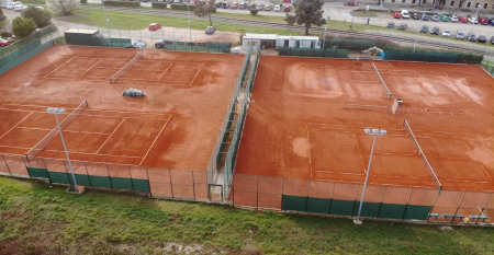 Luftaufnahme der mediterranen Stadt mit dem Hotel Villa Letan, das f&uuml;r seinen Wert bekannt ist und rote Ziegeld&auml;cher, einen Pool, einen Sportplatz und &uuml;ppiges Gr&uuml;n unter einem klaren blauen Himmel aufweist.