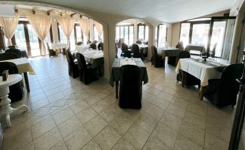 Luftaufnahme der mediterranen Stadt mit dem Hotel Villa Letan, das für seinen Wert bekannt ist und rote Ziegeldächer, einen Pool, einen Sportplatz und üppiges Grün unter einem klaren blauen Himmel aufweist.
