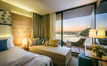Luftaufnahme des Valamar Padova Hotels 4* – eines Resorts an der Küste mit Pool, Sonnenliegen, Strohsonnenschirmen, Palmen und direktem Zugang zu einem Sandstrand in der Nähe einer historischen Küstenstadt bei Sonnenuntergang. Die Gäste können vielfältige