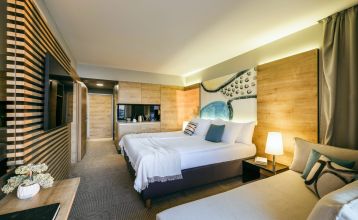 Luftaufnahme des Valamar Padova Hotels 4* – eines Resorts an der Küste mit Pool, Sonnenliegen, Strohsonnenschirmen, Palmen und direktem Zugang zu einem Sandstrand in der Nähe einer historischen Küstenstadt bei Sonnenuntergang. Die Gäste können vielfältige