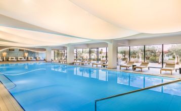 Luftaufnahme des Valamar Padova Hotels 4* – eines Resorts an der Küste mit Pool, Sonnenliegen, Strohsonnenschirmen, Palmen und direktem Zugang zu einem Sandstrand in der Nähe einer historischen Küstenstadt bei Sonnenuntergang. Die Gäste können vielfältige