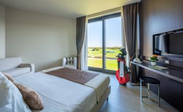 Luftaufnahme der üppigen Fairways, Sandbunker, Wasserhindernisse und des markanten Clubhauses mit sechseckigem Dach des Albarella Golf Hotels – ideal zur Erholung und für eine ruhige Atmosphäre nach dem Sport.