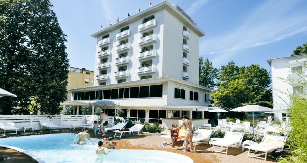 Außenansicht des Hotel RIZ mit Pool, Liegestühlen und spielenden Kindern.