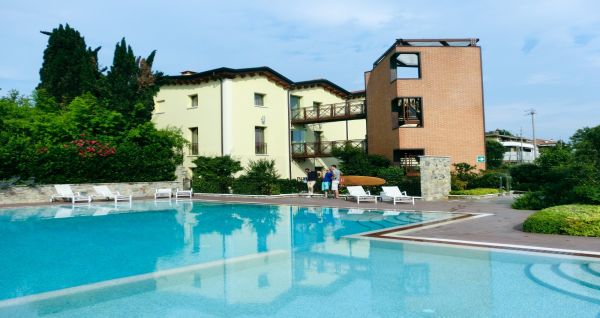 Außenansicht des Hotels Ziba & Spa mit Pool, Liegestühlen, umgeben von Bäumen und Pflanzen.