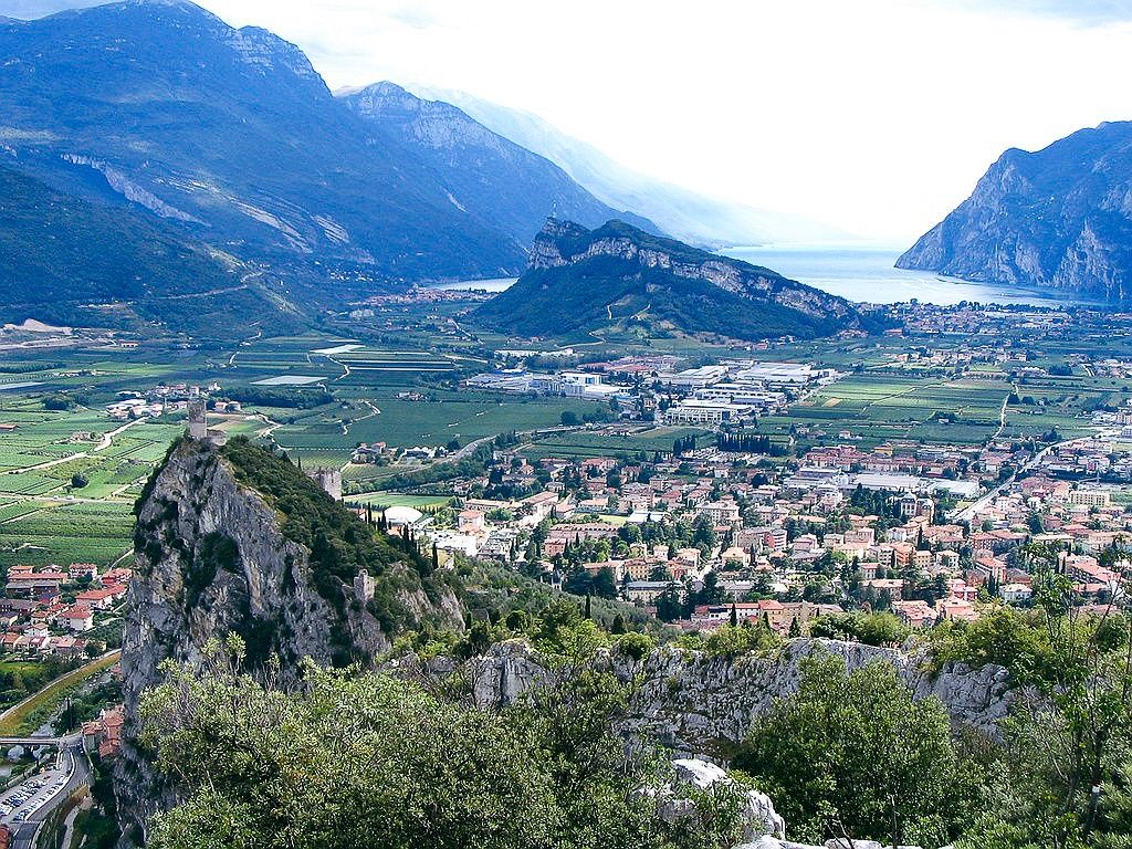 Panoramablick auf eine Stadt in einem Tal, umgeben von Bergen und einem See im Hintergrund.