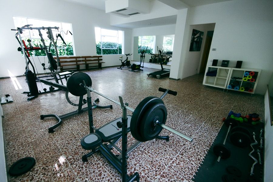 Fitnessraum mit Trainingsgeräten und Gewichten. 