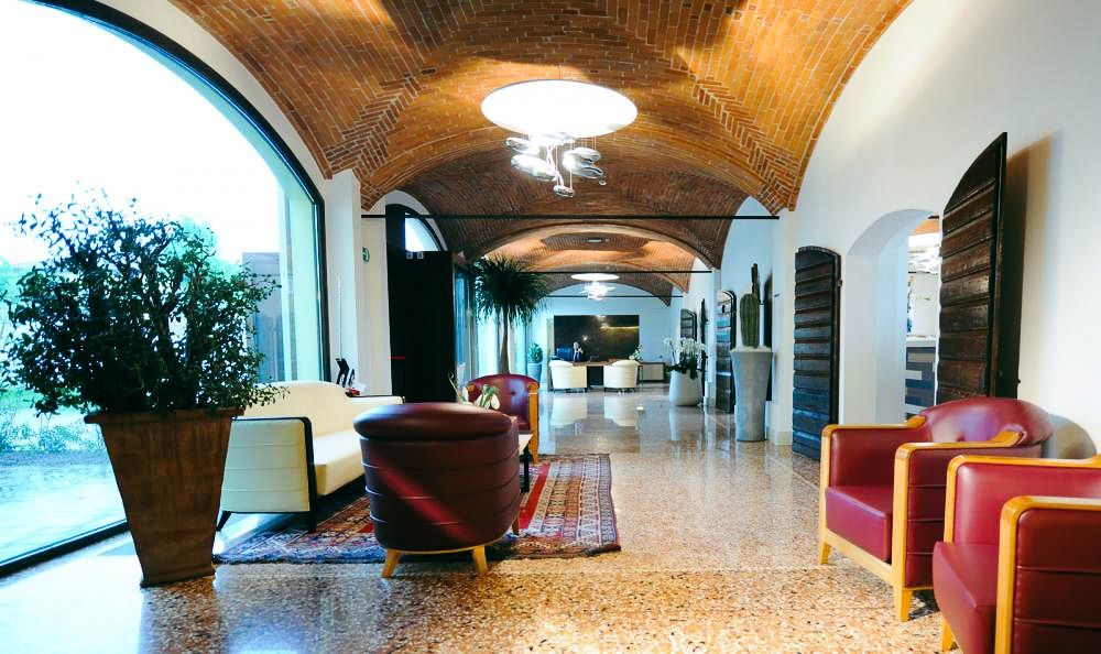 Hotel-Lobby mit Backstein-Gewölbedecke, gemütlichen Sesseln, großen Fenstern und Pflanzen.