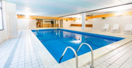 Außenansicht der Hotelanlage La Pertica mit Pool, Sonnenschirmen und Garten, eingebettet in eine Berglandschaft.