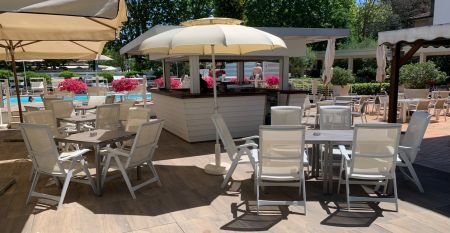 Außenansicht des Hotel RIZ mit Pool, Liegestühlen und spielenden Kindern.