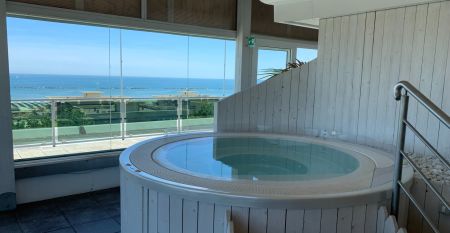 Außenansicht des Hotel RIZ mit Pool, Liegestühlen und spielenden Kindern.