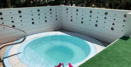 Außenansicht des Hotel RIZ mit Pool, Liegestühlen und spielenden Kindern.