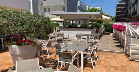 Außenansicht des Hotel RIZ mit Pool, Liegestühlen und spielenden Kindern.
