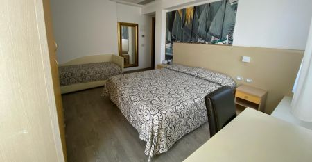 Außenansicht des Hotel RIZ mit Pool, Liegestühlen und spielenden Kindern.