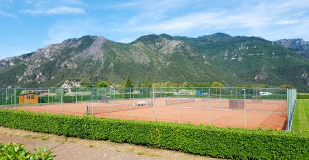 Außenansicht der Hotelanlage La Pertica mit Pool, Sonnenschirmen und Garten, eingebettet in eine Berglandschaft.