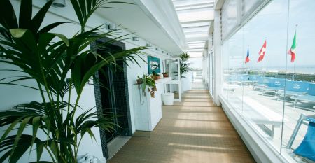 Außenansicht des Hotel RIZ mit Pool, Liegestühlen und spielenden Kindern.