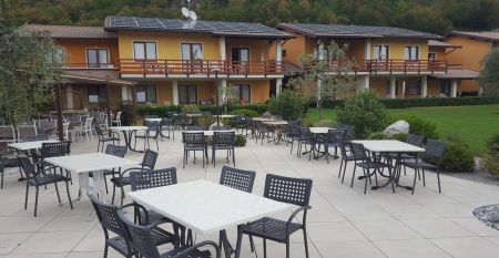 Außenansicht der Hotelanlage La Pertica mit Pool, Sonnenschirmen und Garten, eingebettet in eine Berglandschaft.
