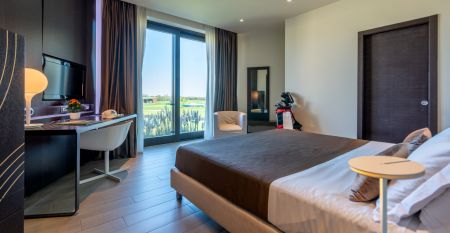 Luftaufnahme der &uuml;ppigen Fairways, Sandbunker, Wasserhindernisse und des markanten Clubhauses mit sechseckigem Dach des Albarella Golf Hotels &ndash; ideal zur Erholung und f&uuml;r eine ruhige Atmosph&auml;re nach dem Sport.