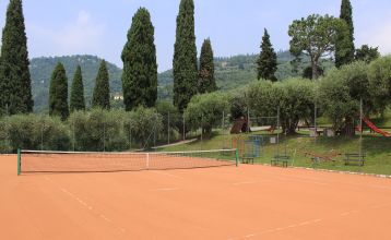 Gartenrestaurant des Hotel Sportsman mit Rattanmöbeln, Sonnenschirmen und gedeckten Tischen auf gepflegtem Rasen.