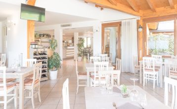 Außenansicht der Hotelanlage La Pertica mit Pool, Sonnenschirmen und Garten, eingebettet in eine Berglandschaft.