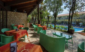 Eingang des Sporthotels Olimpo mit Steinfassade, Hotelname und Sternenmarkierung, umgeben von Pflanzen und Bäumen.
