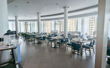Außenansicht des modernen Hotel Capo Nord mit runder Architektur, Holzverkleidung und Balkonen, eingebettet in eine grüne Gartenlandschaft.