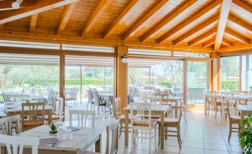 Außenansicht der Hotelanlage La Pertica mit Pool, Sonnenschirmen und Garten, eingebettet in eine Berglandschaft.