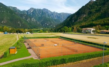 Außenansicht der Hotelanlage La Pertica mit Pool, Sonnenschirmen und Garten, eingebettet in eine Berglandschaft.