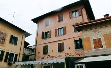 Außenansicht des Hotels mit traditioneller Fassade, Holzfensterläden und Restaurant-Markise.
