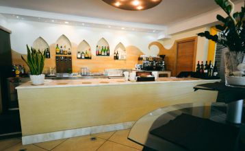 Außenansicht des Hotel RIZ mit Pool, Liegestühlen und spielenden Kindern.