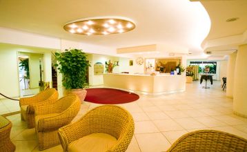 Außenansicht des Hotel RIZ mit Pool, Liegestühlen und spielenden Kindern.