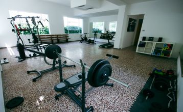 Außenansicht des Hotel RIZ mit Pool, Liegestühlen und spielenden Kindern.